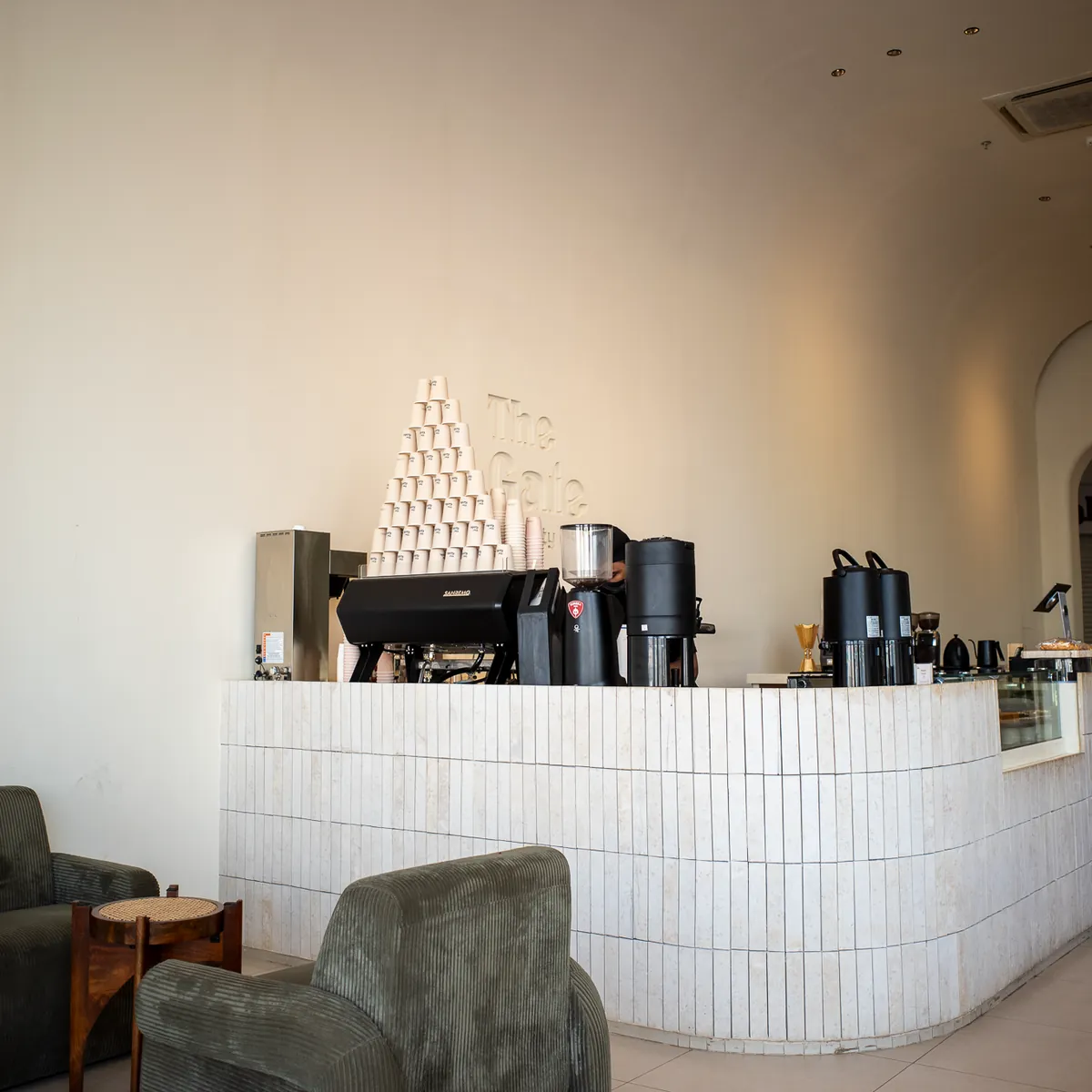 A coffee bar with a white tiled counter and a green armchair.