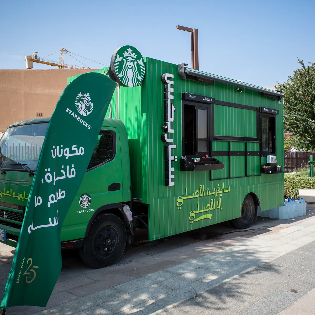 A green Starbucks coffee truck with Arabic lettering.