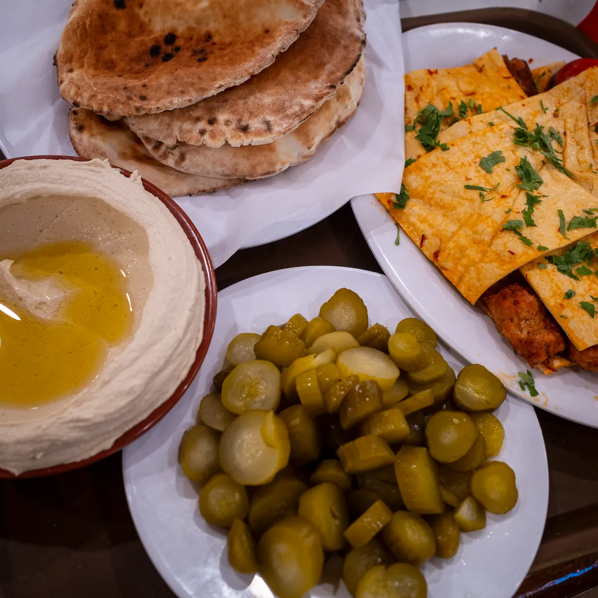 Hummus, bread, pickles and eggs on a table.
