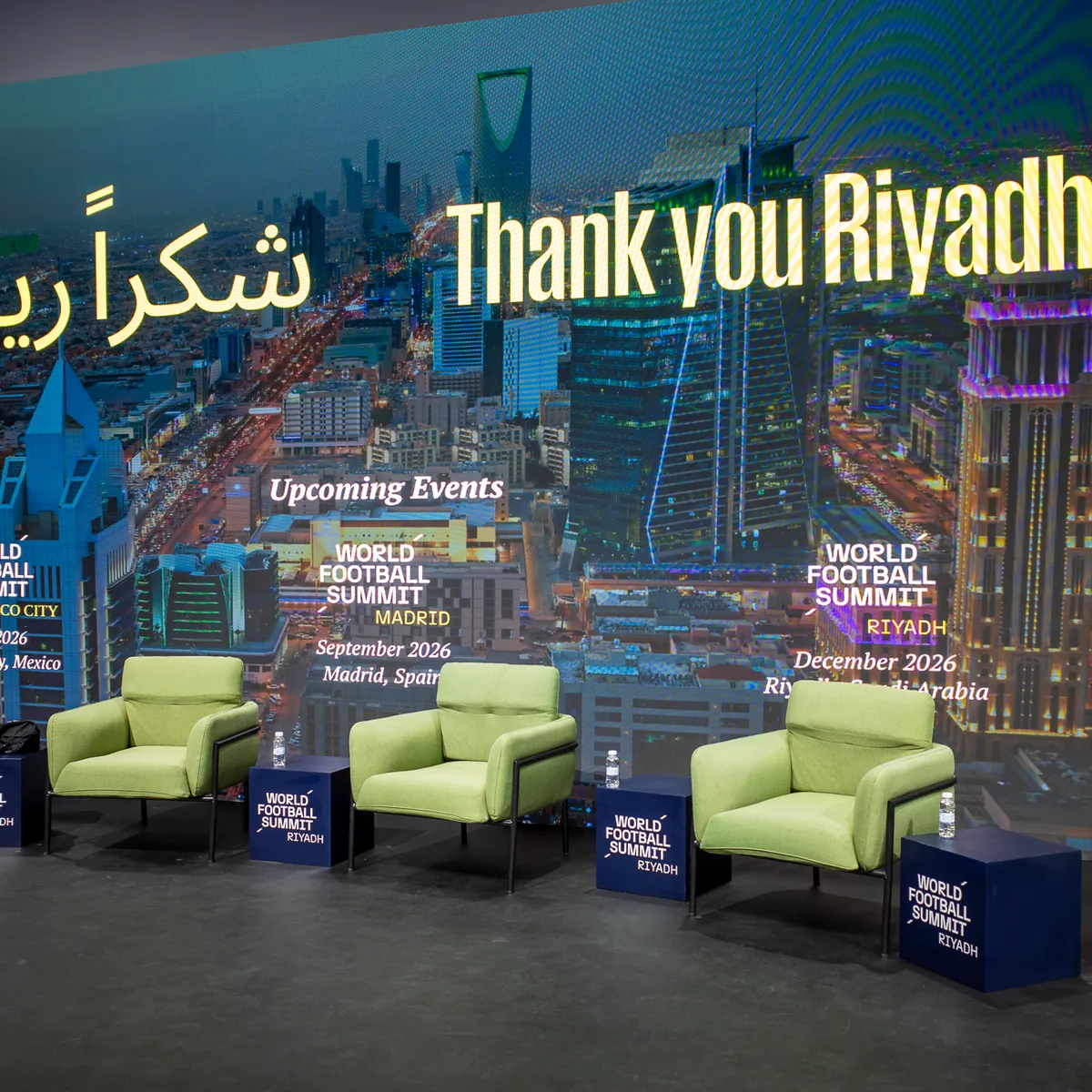 A stage screen reading Thank you Riyadh above empty lounge chairs.
