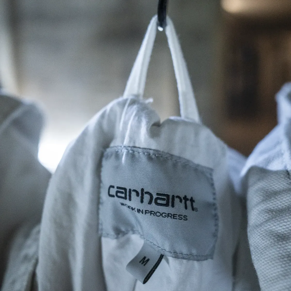 Close-up of a Carhartt Work in Progress label inside a pale jacket.